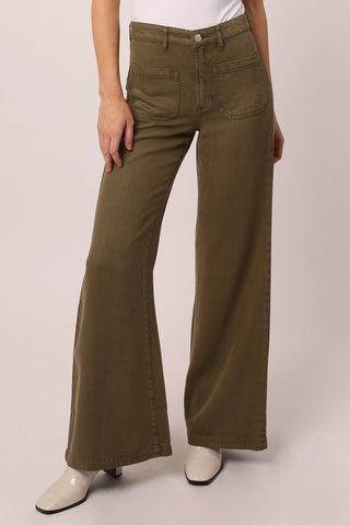 Person wearing olive green flared pants on a plain background