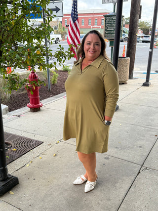 Woman in a green dress standing on a sidewalk with a street scene in the background