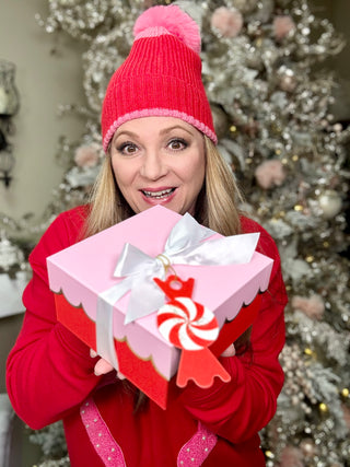 Woman wearing pink and red hat with pink and red sweatshirt holding a pink and red box