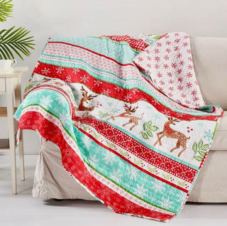 Colorful quilt with reindeer design draped over a sofa in a living room setting.