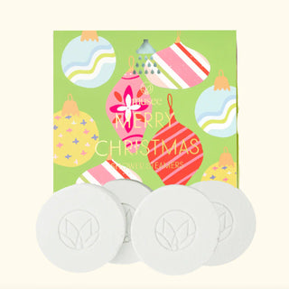 Set of white bar soaps with a 'Merry Christmas' themed packaging featuring colorful ornaments on a green background.