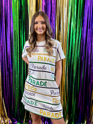 Woman wearing a 'Parade' themed dress in front of colorful fringe curtains