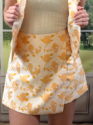 Person wearing a floral skort with orange flowers on a white background