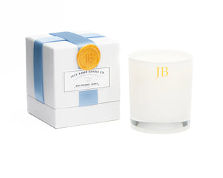 A box with a blue ribbon and white candle next to it