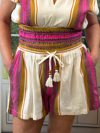 Person wearing a colorful striped top and shorts with tassels.